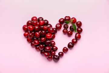 Heart shape made of sweet cherry on color background