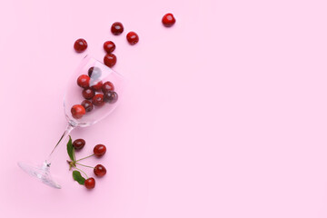 Glass with sweet cherry on color background