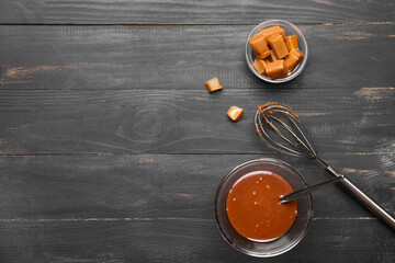 Bowls with liquid caramel and candies on table