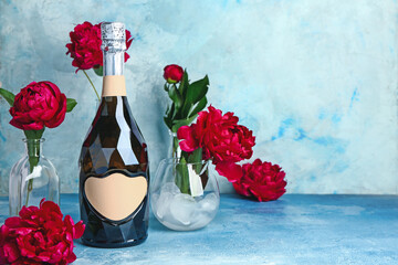 Bottle of champagne and flowers on color background