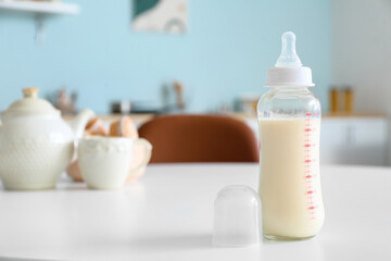 Bottle of milk for baby on table in kitchen