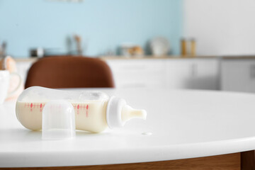 Bottle of milk for baby on table in kitchen