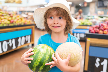 Child holding watermelon in supermarket. Sale, consumerism and kids concept. Vegetables in store.