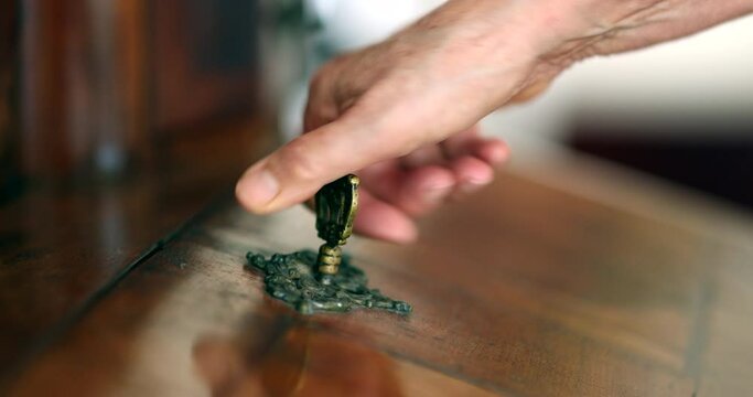 Close-up hand removing key from antique furniture