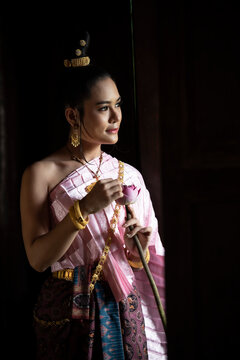 Portrait  of a beautiful woman in Thai old suit or Thai national dress suit looks elegant and charming in Old antique Thai houses/Old Thai fashion model concept