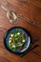 Spinach and mozzarella salad with cherry tomatoes and chili slices, classic salad served with white wine, a posh modern restaurant