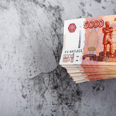 Russian cash banknotes of five thousand rubles, the bundle hangs on a gray background.