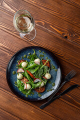 Spinach and mozzarella salad with cherry tomatoes and chili slices, classic salad served with white wine, a posh modern restaurant