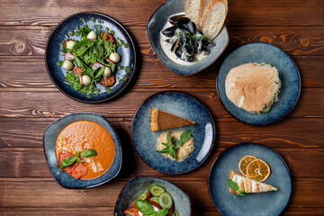 Assortment of european meals, placed in a circle, on a wooden table, above view