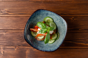 Simple vegetable salad with cucumbers and tomatoes on wooden table, top view
