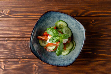 Simple vegetable salad with cucumbers and tomatoes on wooden table, top view