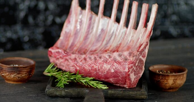 A large piece of raw rack of lamb slowly rotates. 