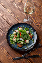 Spinach and mozzarella salad with cherry tomatoes and chili slices, classic salad served with white wine, a posh modern restaurant