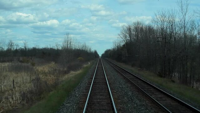 looking outside through the back window of a moving train while the rails  leave the departing point
