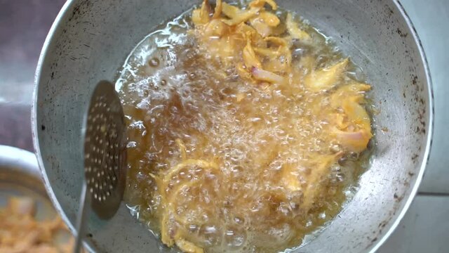 Turning Fried Onion (Onion Pakoda) Using Stainless Steel Skimmer On A Pan With Boiling Oil In India. - Close Up Shot