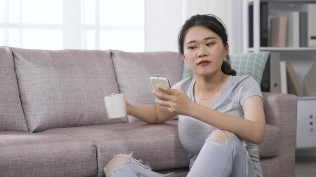 asian japanese woman amused by interesting news feed while browsing posts on social media website by smartphone.