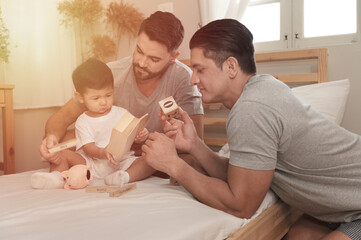 Young married LGBT parent couples play with adopted child in bedroom