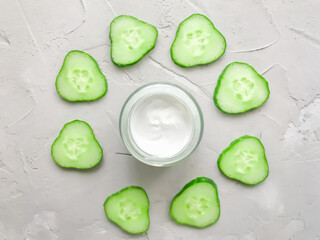 Cream on a textured background, with cucumbers. Cucumber-based cosmetics. Natural cosmetic. Moisturizing cream.