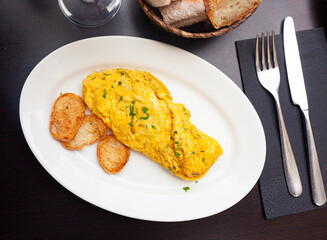Tender rolled french omelet with filling of ham, cheese and chopped parsley served with croutons