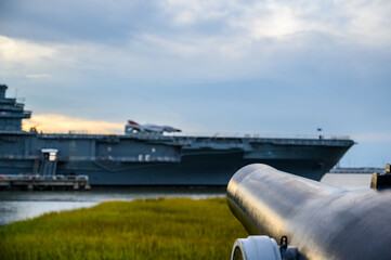 Antique cannon aimed at a modern aircraft carrier