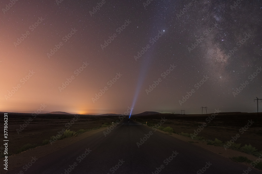 Wall mural milky way on night sky and standing man silhouette on road with flashlight . colorful night landscap