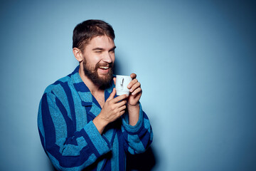 man in striped blue robe holding white cup in hand and emotions fun surprise model cropped view