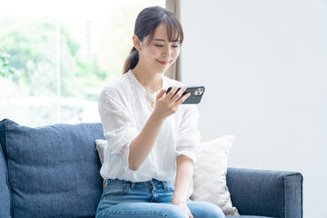 家で携帯を触るアジア人女性
