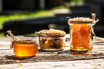 Honey in glass jar with bee flying on wooden table on background honeycombs with full cells of honey. organic natural ingredients concept. banner, menu, recipe, place for text
