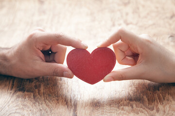 Fototapeta premium Male and female hands holding red heart.