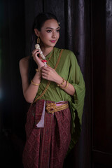 Portrait  of a beautiful woman in Thai old suit or Thai national dress suit looks elegant and charming in Old antique Thai houses/Old Thai fashion model concept