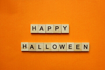 Words Happy Halloween. Wooden blocks with an inscription on an orange background. Bulletin board. The concept of the holiday is Halloween. The view from the top. Copy space