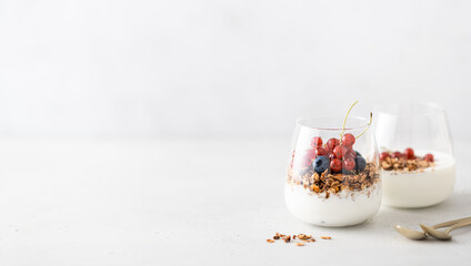 Breakfast, granola with yogurt and berries in a jar on a light background