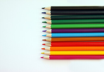 Colored pencils on a white background. Lots of different colored pencils. Colored pencil. Pencils are very sharp. Pencils are on the right, exactly. Close-up. Copy space. Background. Flat lay