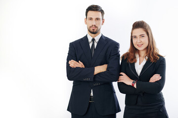 Studio portrait of smiling confident businessman and businesswoman standing with arms folded