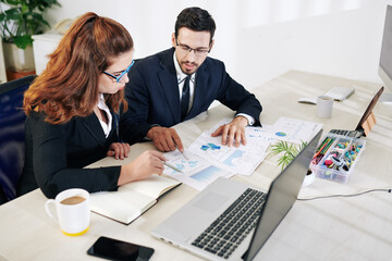 Marketing team checking financial documents at meeting and discussing incomes and expenses