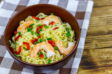 Bowl of instant Chinese noodles with shrimps, green onion and red hot chilli peppers on wooden table