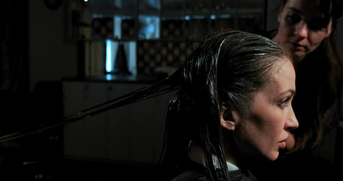 professional hairdressers apply special balms and fire cut technique on beauty salon visitor hair slow motion closeup