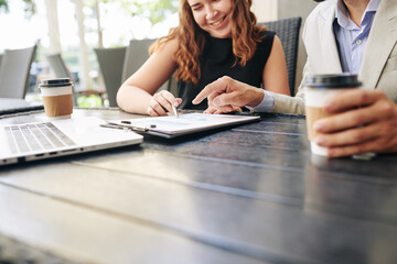 Smiling business people analyzing financial report when having meeting in outdoor cafe