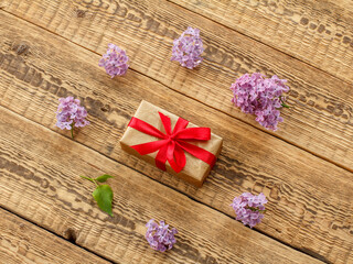 Gift box and lilac flowers on wooden boards.