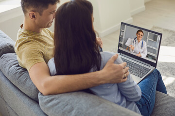 Online consultation with doctors. Couple listens to doctor online using laptop in room....
