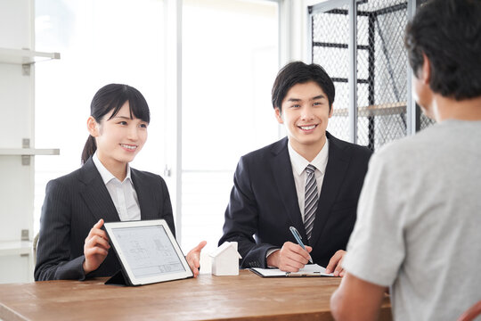 タブレットを使って部屋の説明をする日本人不動産営業職