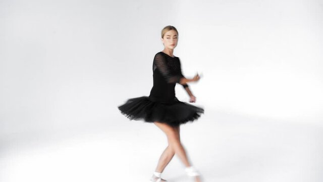 Graceful ballerina performing classical dancing moves on white background