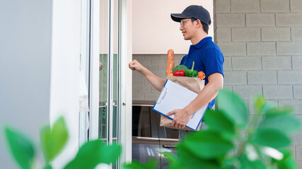 Asian deliver man in uniform is delivering the paper bag waiting for the customer in front of the...
