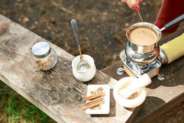 Hot drink on nature. Process of cooking coffee with spices in nature. Background - camping and forest. Active rest.