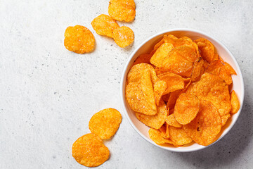Spicy potato chips in white bowl, gray background, top view. Fast food concept.