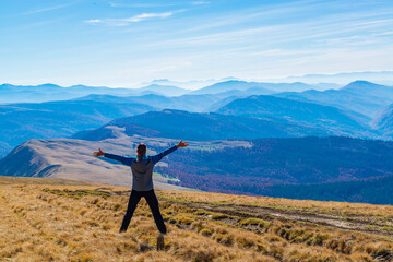 Fototapeta premium Man with raised arms on the mountain top with a view.