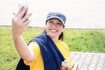 Smiling senior sportswoman doing selfie outdoors in the park