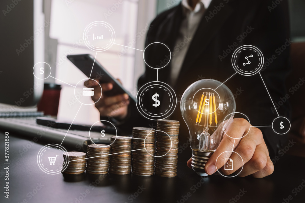 Poster business hand holding lightbulb with using laptop computer and money stack in office. idea saving en