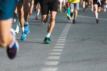 A close-up of the legs of the running track and field athletes on the asphalt. Marathon runners in special sneakers