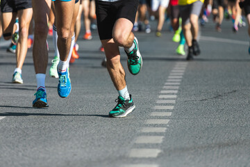 A close-up of the legs of the running track and field athletes on the asphalt. Marathon runners in special sneakers
